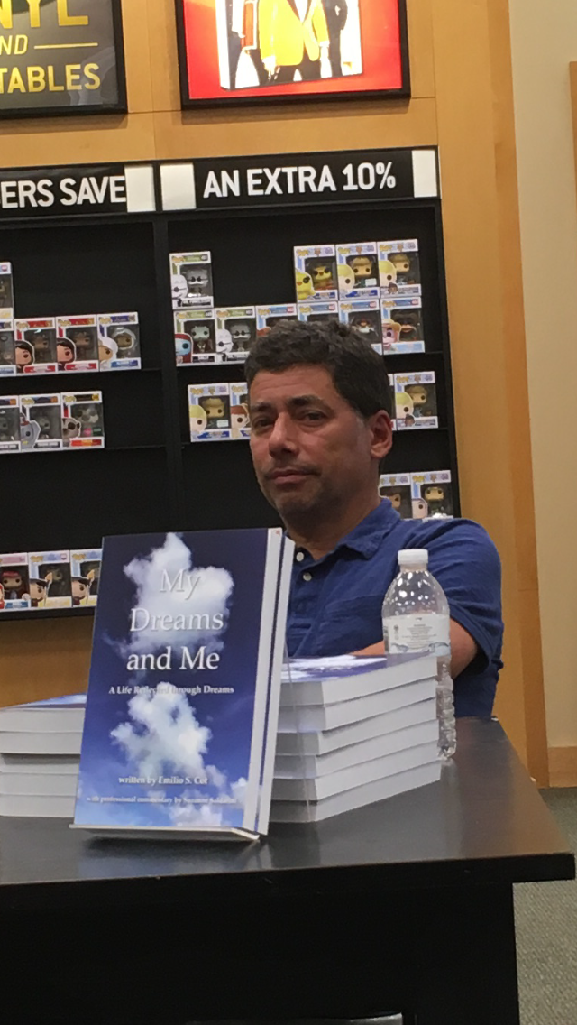 Emilio poses with book at book signing event